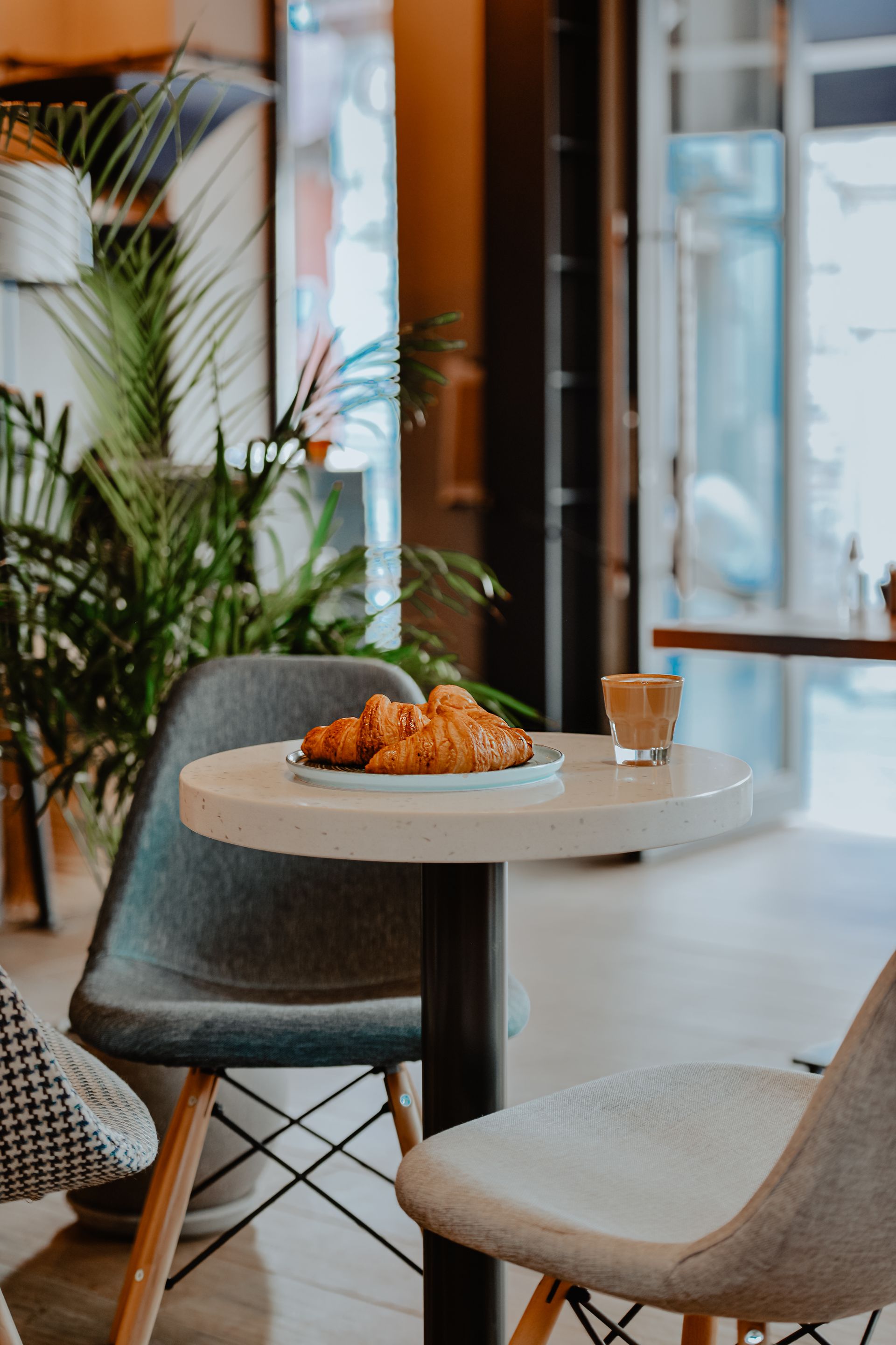 Coffee and a croissant at a light-filled café table