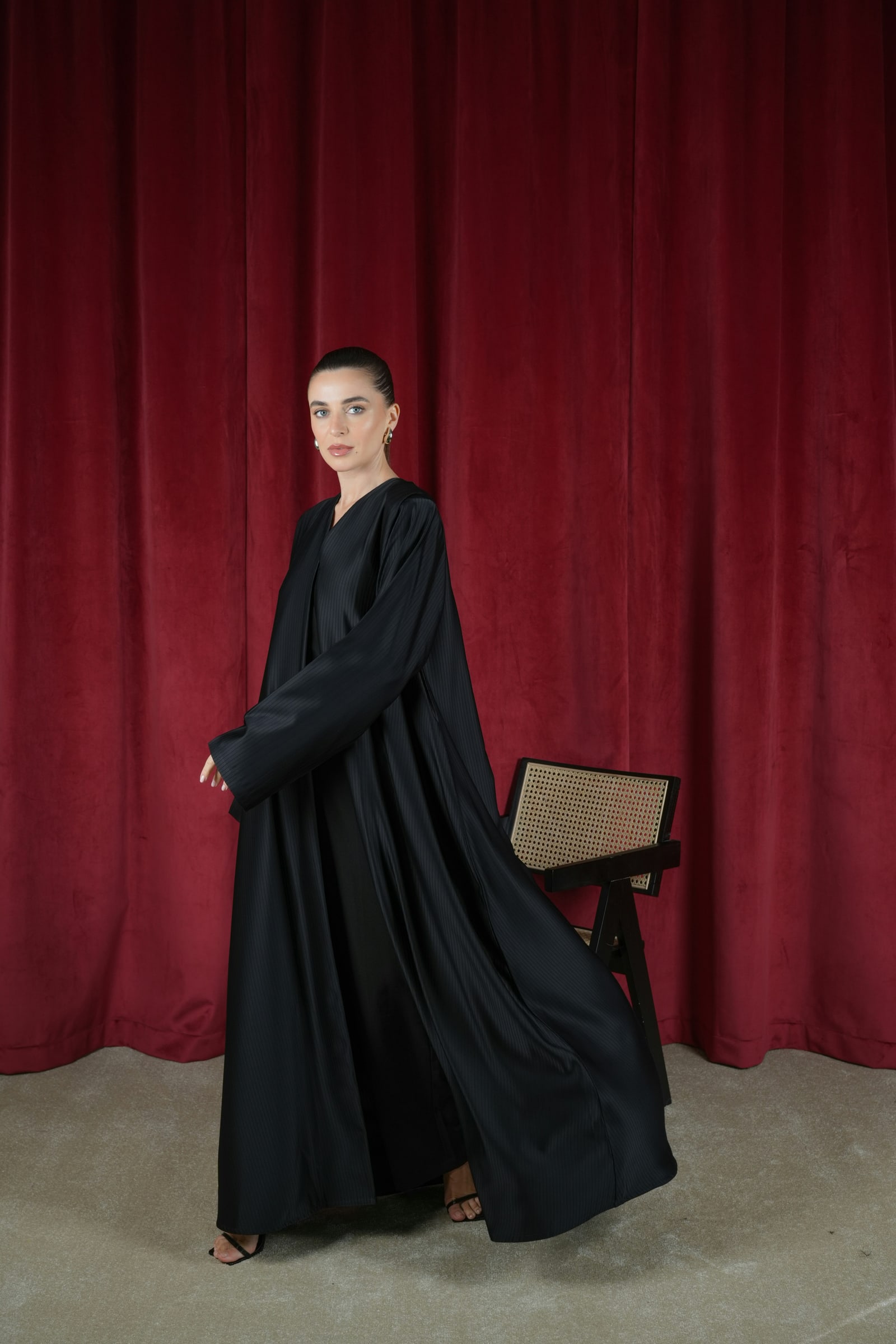 Flowing black abaya against a burgundy backdrop