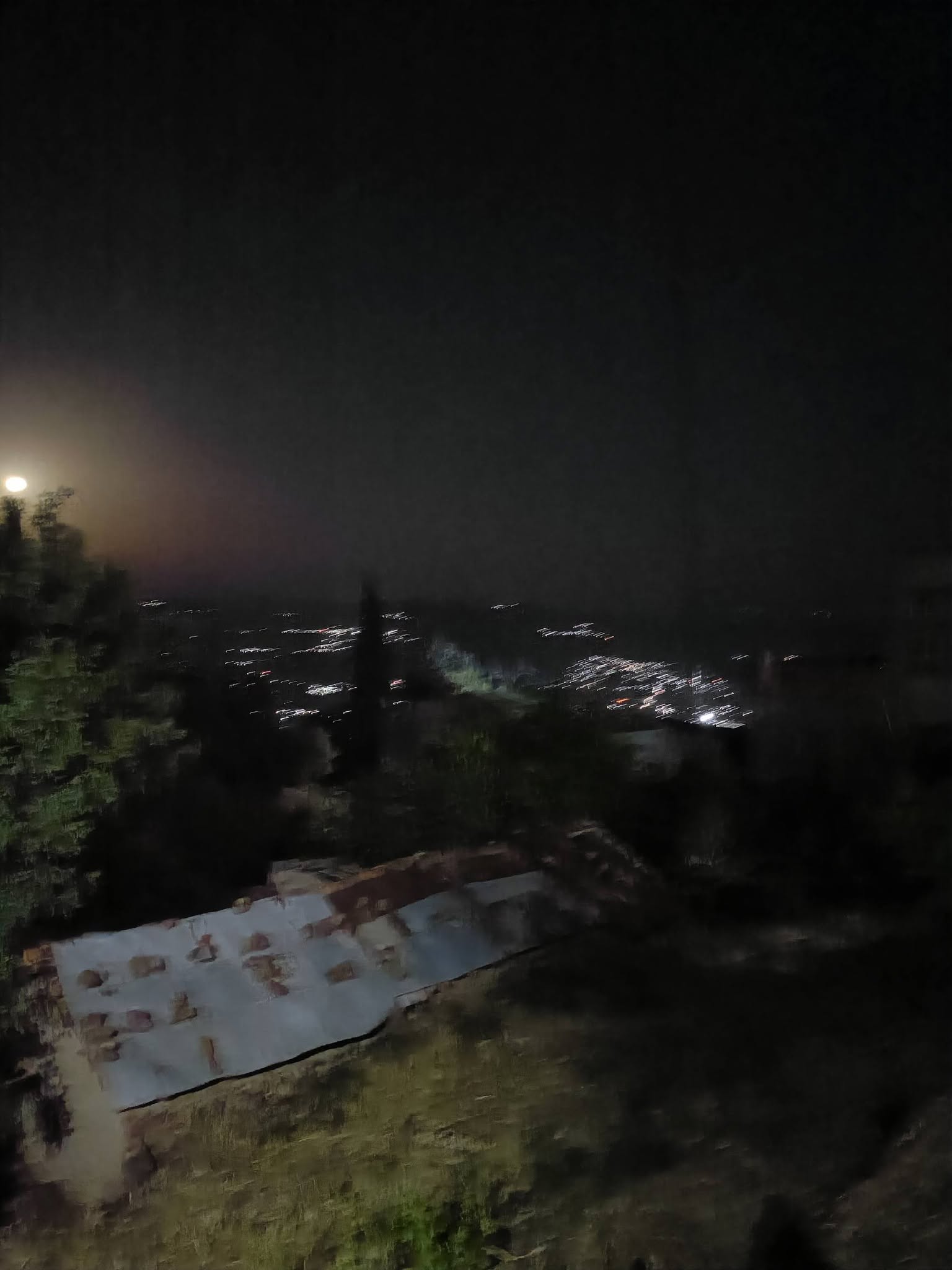 Les lumières d’un village et une lune brillante dans la nuit.