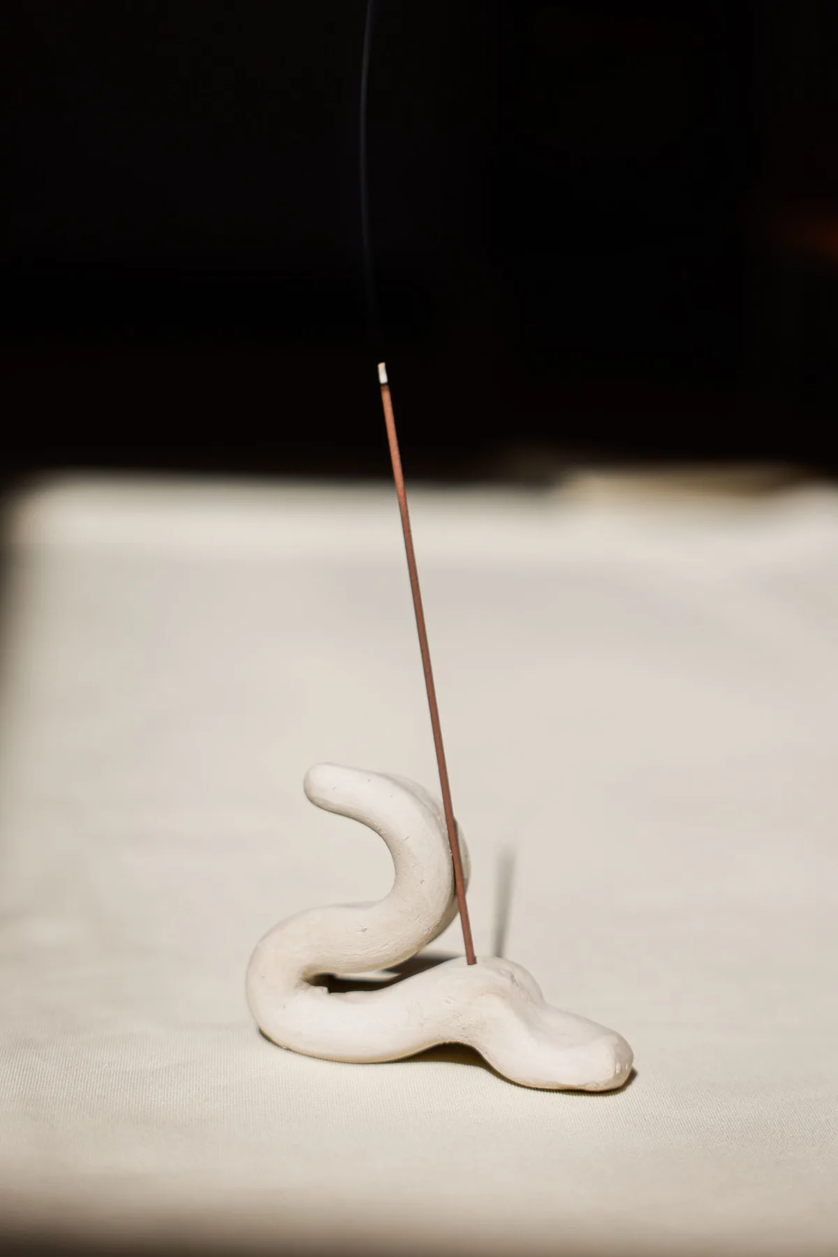 A minimalist ceramic incense holder in soft light